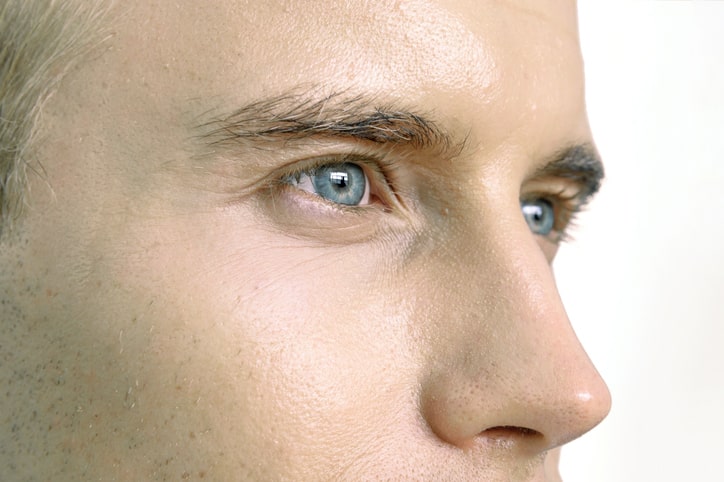 extreme close up of side of man's upper face with solid white background