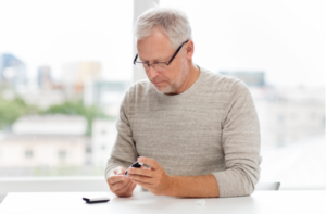 senior man with glucometer checking blood sugar level at home