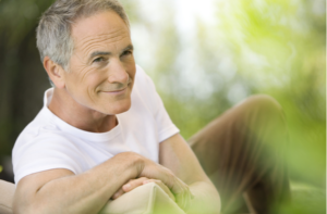 Happy middle aged man reclining on deck chair in garden