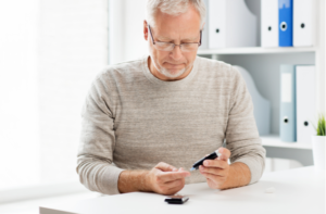 senior man with glucometer checking blood sugar level