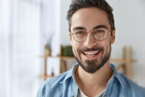 Close up shot of attractive male with smile wears spectacles