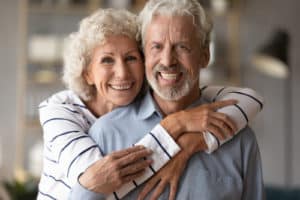middle aged couple with woman cuddling from back smiling