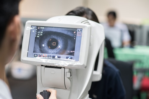 Woman looking at refractometer eye test machine in ophthalmology