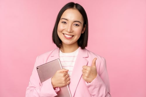 girl in office in business suit holding digital tablet showing thumbs up.